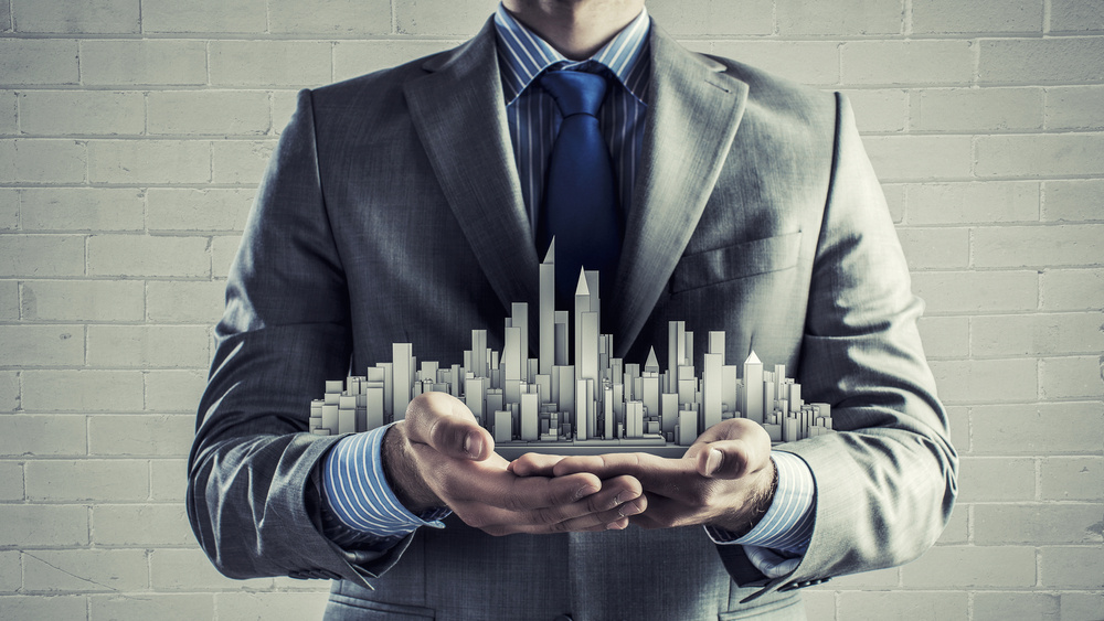 Close up of businessman hand holding construction model Close up of businessman hand holding construction model